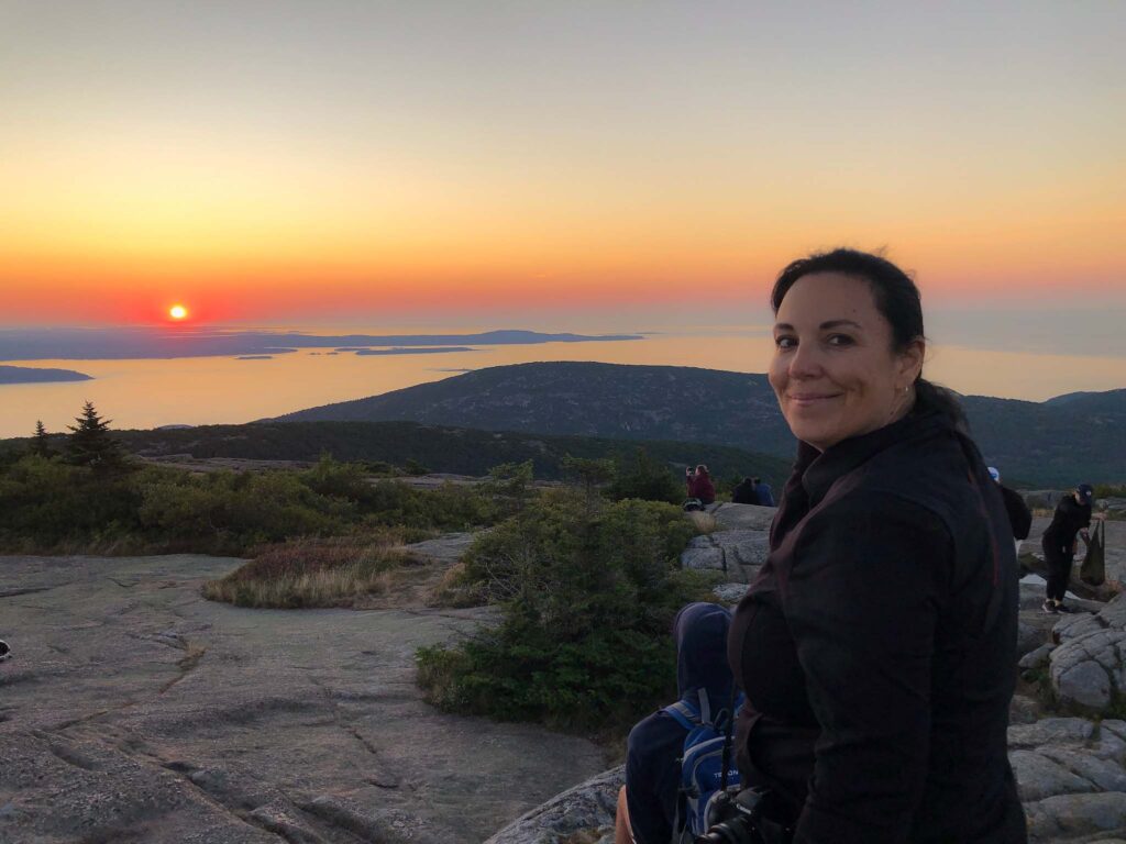 Kathy - VegInspired - woman sitting on mountain overlooking ocean at sunrise